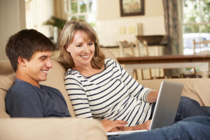 Mother With Teenage Son Sitting On Sofa At Home